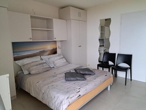 a bedroom with a large bed and two chairs at App KLIF De Panne - top location & sea front !! in De Panne