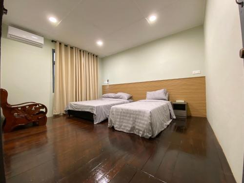 a bedroom with two beds and a wooden floor at THE SPACE SRI AMAN in Simanggang
