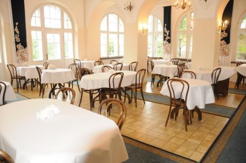 a dining room with white tables and chairs at Czerwony Dwór in Krynica Zdrój