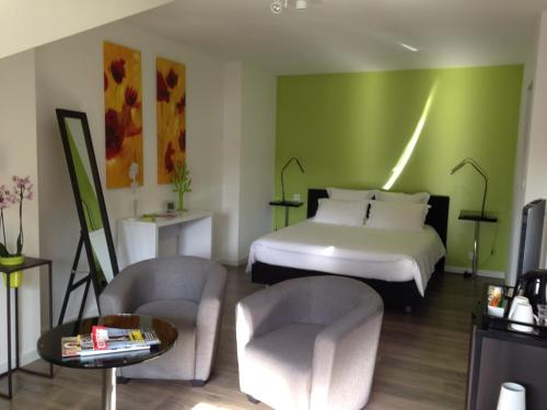 a hotel room with a bed and a couch and chairs at Les Chambres Lauryvan in Saint-Junien