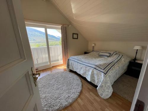 a bedroom with a bed and a large window at Koselig hus med fin utsikt 