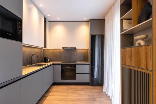 a kitchen with wooden floors and white cabinets at The five star apartment in Thessaloniki