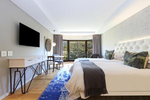 a bedroom with a bed and a desk with a television at Vineyard Hotel in Cape Town