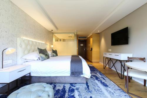 a bedroom with a bed and a desk and a television at Vineyard Hotel in Cape Town