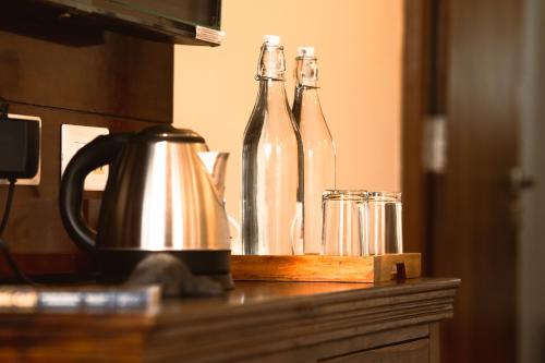 two bottles on a counter with a kettle and glasses at RajBagh by Aaryam in Sawāi Mādhopur