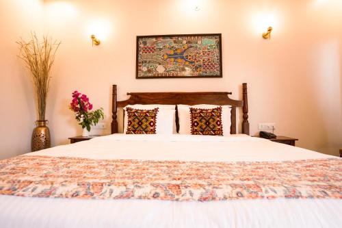 a bedroom with a bed with white sheets and pillows at RajBagh by Aaryam in Sawāi Mādhopur
