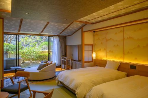 a bedroom with two beds and a chair and a window at Fukuichi in Shibukawa