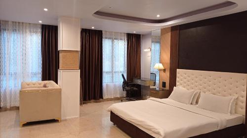 ein Schlafzimmer mit einem großen Bett und einem Stuhl in der Unterkunft The Grand Hotel in Aizawl