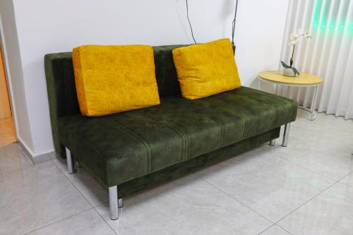 a green couch with two yellow pillows on it at דירת יהלום חדשה ומודרנית 5 דקות נסיעה מהים in Ashqelon