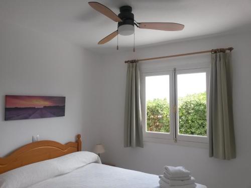 una camera da letto con ventilatore a soffitto e finestra di Apartamentos Ses Anneres a Cala en Blanes