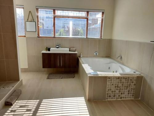 a large bathroom with a tub and a sink at Luxury Living On Westview in Port Elizabeth
