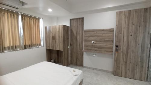 a bedroom with a white bed and wooden cabinets at Hotel Jay Palace Inn in Solapur