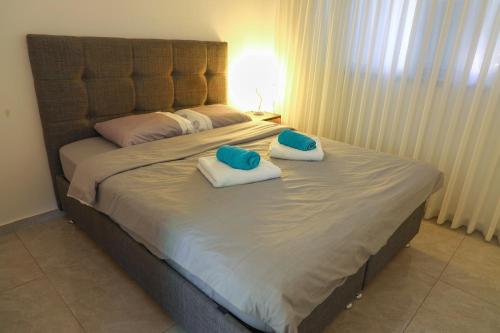 a large bed with two blue pillows on it at דירת יהלום חדשה ומודרנית 5 דקות נסיעה מהים in Ashqelon