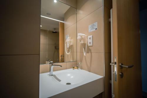 a bathroom with a sink and a mirror at Eleven Business & Sport Hotel in Jászárokszállás