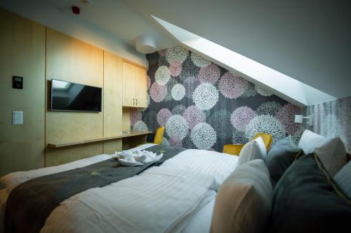 a bedroom with a bed and a tv on a wall at Eleven Business & Sport Hotel in Jászárokszállás