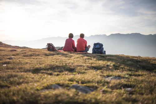 two people sitting on a hill looking at the view at Pöder - daheim in den Bergen in Ultimo