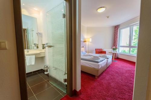 a bedroom with a bed and a bathroom with a shower at Einklang - Dein Hotel am Südhorn in Wendisch Rietz
