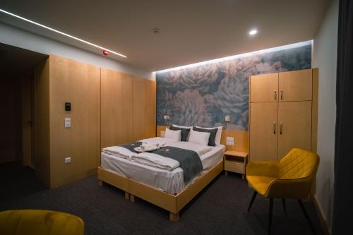 um quarto com uma cama e uma cadeira amarela em Eleven Business & Sport Hotel em Jászárokszállás