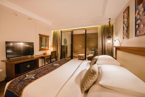 a hotel room with a bed and a television at Ramayana Suites and Resort in Kuta