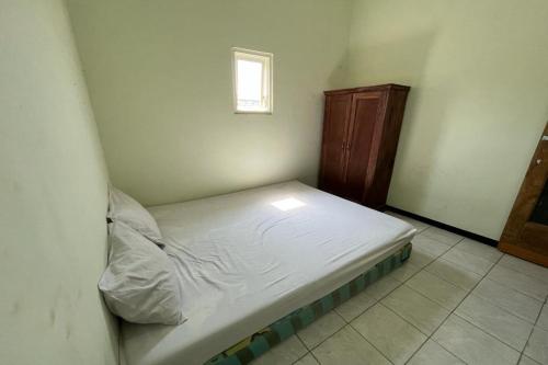 Cama pequeña en habitación con ventana en OYO Life 92982 Kost Berkah Ibu, en Lawang