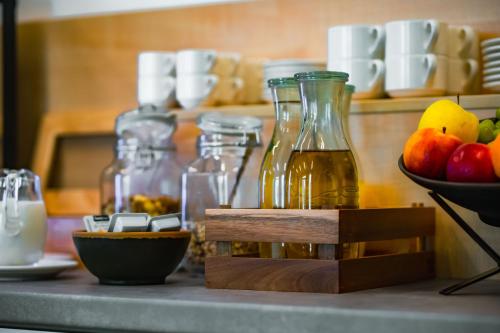 a counter with bottles of oil and a bowl of fruit at Eleven Business & Sport Hotel in Jászárokszállás