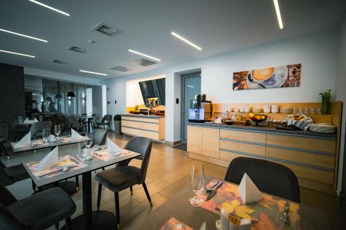 a restaurant with tables and chairs and a kitchen at Eleven Business & Sport Hotel in Jászárokszállás