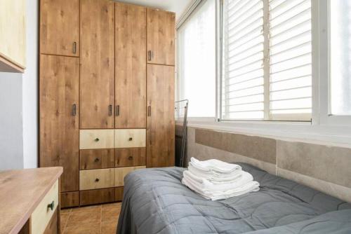 a bedroom with wooden cabinets and a bed with towels on it at "One minute from sea" from Shneider Apartments in Haifa