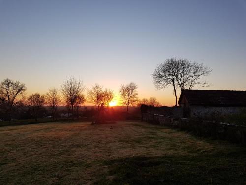a sunset in a field with trees and a fence at Le clos des sources in Isigny-sur-Mer