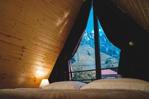 a bedroom with a large window with a mountain view at Luno Cottage in Stepantsminda