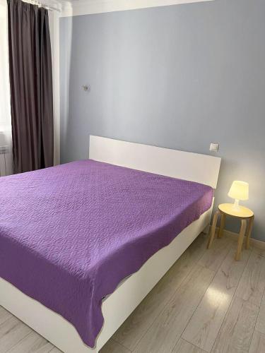 a bed with a purple comforter in a bedroom at Sunny Home in Oral