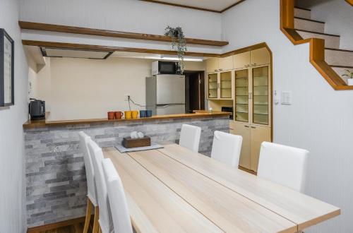a kitchen with a wooden table and white chairs at HANASTAY花渓居 野田Noda in Osaka