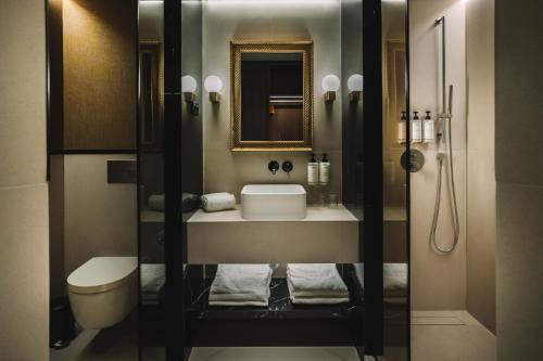 a bathroom with a sink and a toilet and a mirror at Hotel Pinar Plaza in Madrid