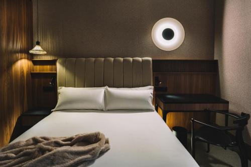 a bedroom with a bed and a desk and a white lamp at Hotel Pinar Plaza in Madrid