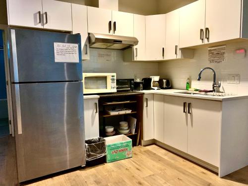 a kitchen with white cabinets and a stainless steel refrigerator at Deluxe House in Surrey