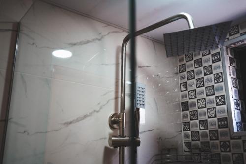 a shower in a bathroom with white marble walls at Luno Cottage in Stepantsminda