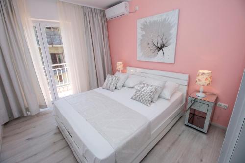 a bedroom with a white bed and a pink wall at APARTMAN KSENIJA KOVAČIĆ in Stanići