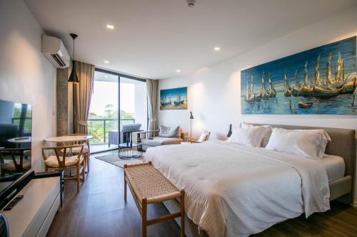 a bedroom with a large bed and a living room at Escape Condominiums Beachfront Suites - Mae Phim in Rayong