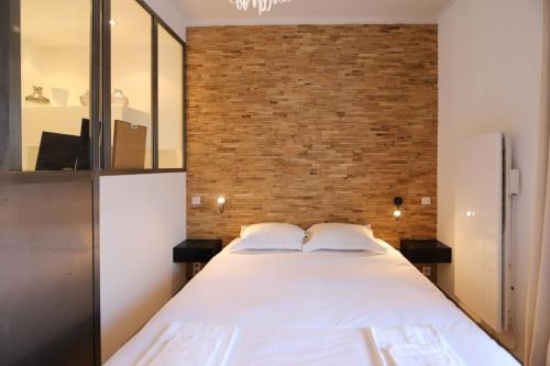 a bedroom with a large white bed with a brick wall at Annecy apt w car park near downtown and lake in Annecy