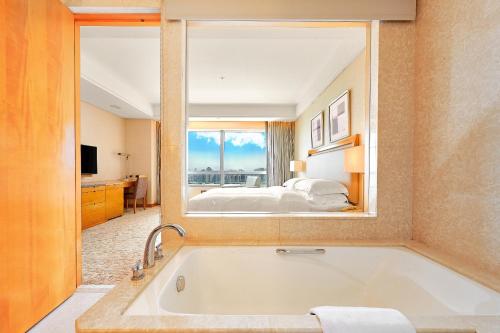 Windsor Hotel Taichung في تايتشونغ: غرفة في الفندق مع حوض استحمام وغرفة نوم