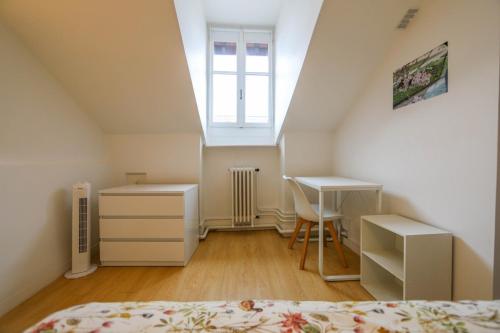 - une chambre mansardée avec un lit, un bureau et une fenêtre dans l'établissement Le Sommeiller - hyper centre avec garage, à Annecy