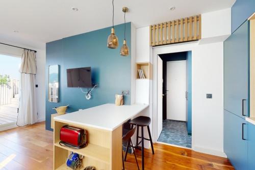 a kitchen with blue walls and a white counter and stool at Des Bulles en rooftop in Annecy