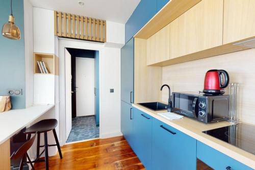 a kitchen with blue cabinets and a red appliance at Des Bulles en rooftop in Annecy
