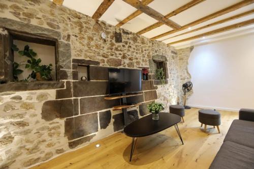 een woonkamer met een stenen muur en een flatscreen-tv bij Le Coeur de Ville splendide T2 plein centre in Annecy
