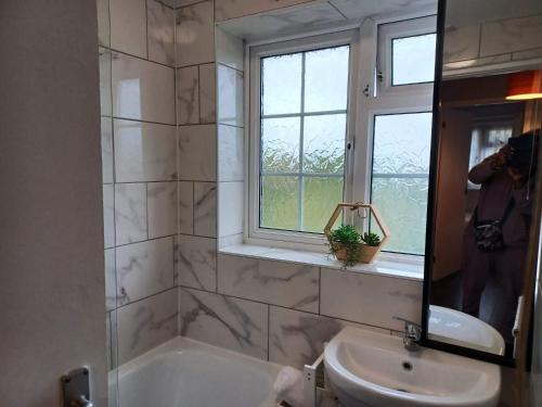 a bathroom with a tub and a sink and a window at Poynters House - Huku Kwetu Luton & Dunstable - Spacious 2 Bedroom House-Private garden and parking in Luton