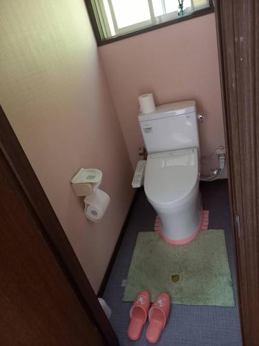 a bathroom with a toilet and a pair of pink slippers at Takumisou1 in Kiso-fukushima