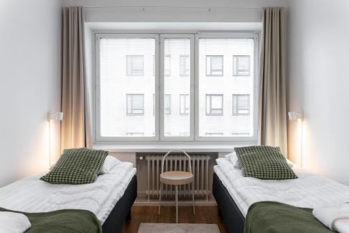two beds in a room with a window at Forenom Serviced Apartments Pori Antinkatu in Pori