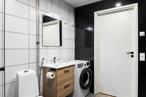 a bathroom with a sink and a washing machine at Forenom Serviced Apartments Pori Antinkatu in Pori