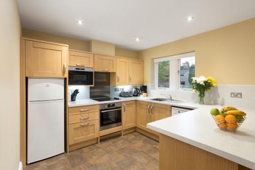 a kitchen with wooden cabinets and a white refrigerator at Thurnham Hall Resort in Cockerham