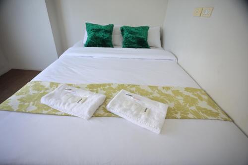 1 cama con 2 almohadas blancas y verdes en Homes by Gilmore Tower Suites, en Manila
