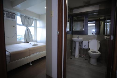 een kleine badkamer met een toilet en een wastafel bij Homes by Gilmore Tower Suites in Manilla